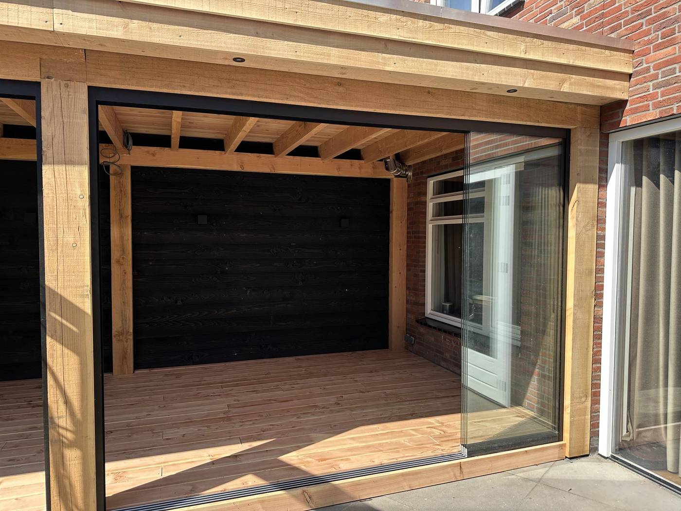 BuitenBinnen buitenkamer met douglas overkapping, glaswand en zwarte wand